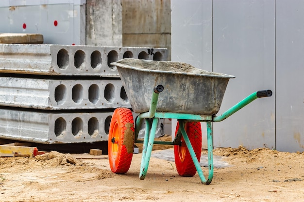 Construction metal wheelbarrow or cart close-up. Transportation of building materials at the construction site. Tool for construction work.