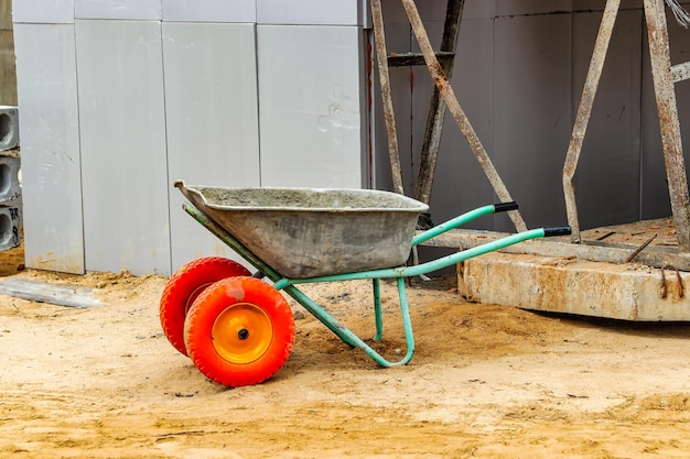 Construction metal wheelbarrow or cart closeup Transportation of building materials at the construction site Tool for construction work