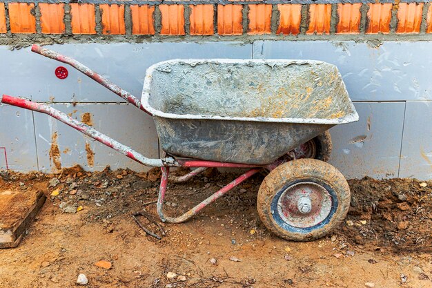 Construction metal wheelbarrow or cart closeup Transportation of building materials at the construction site Tool for construction work