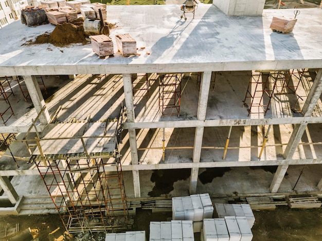 Construction of a monolithic reinforced concrete house Closeup of a building under construction The sun's rays illuminate the construction site Shooting from a drone Modern building in the city