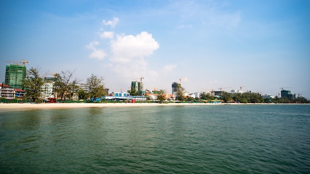 Construction of multi-storey buildings in Cambodia, Sihanoukville. Modern high-rise buildings under construction. Beach with white sand in the city. Many cranes on the shore.