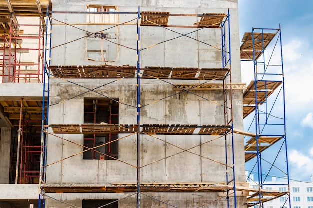 Construction of a new monolithic reinforced concrete house Scaffolding on the facade of a building under construction Working at height on a construction site