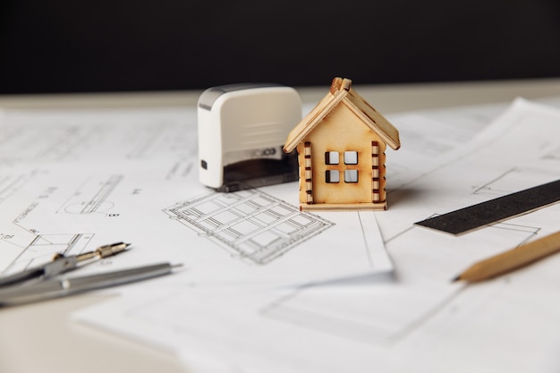 Construction plan with wooden model of house and stamp