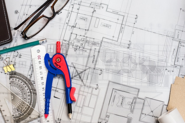 Construction planning drawings on the table with pencils, ruler and glasses on the table, retro effect