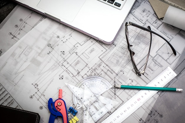 Construction planning drawings on the table with pencils, ruler and glasses on the table, retro effect