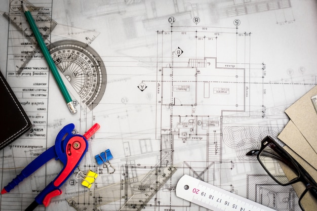 Construction planning drawings on the table with pencils, ruler and glasses on the table, retro effect