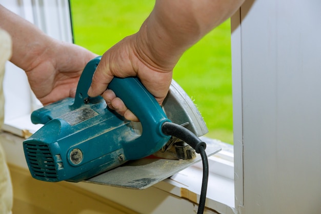 Construction remodeling home cutting wooden trim board on with hand circular saw.