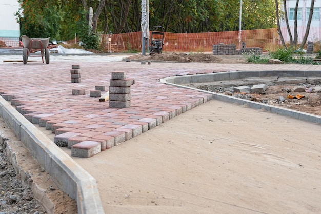 A construction site on the site of laying paving stones, a wheelbarrow and a vibrating plate in the background