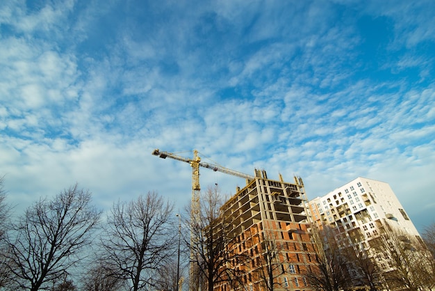 Construction site with crane blue sky with white clouds on background. copy space