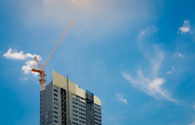 Construction site with crane and building. Real estate industry. Crane use reel lift up equipment in construction site. Building made of steel and concrete.