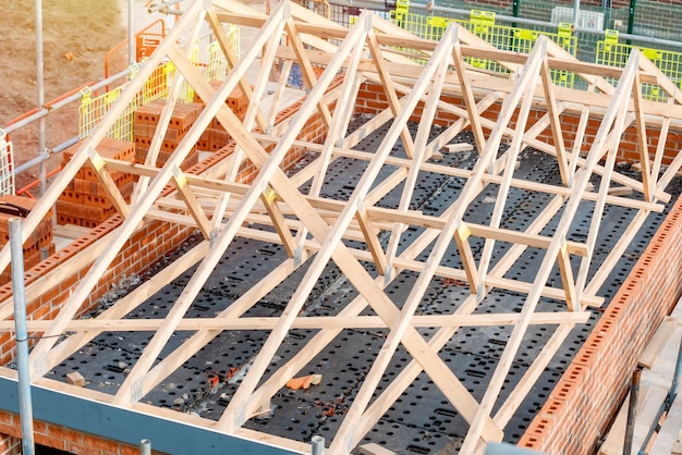 Construction site with a house being built from brick and timber featuring brickwork roof trusses