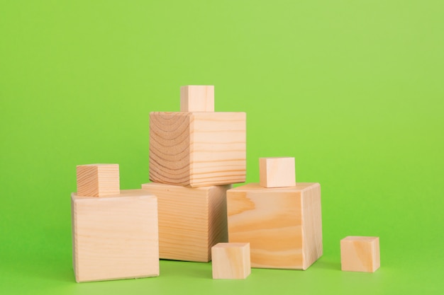 Photo construction of wooden cubes on green background with copy space. mockup composition for design