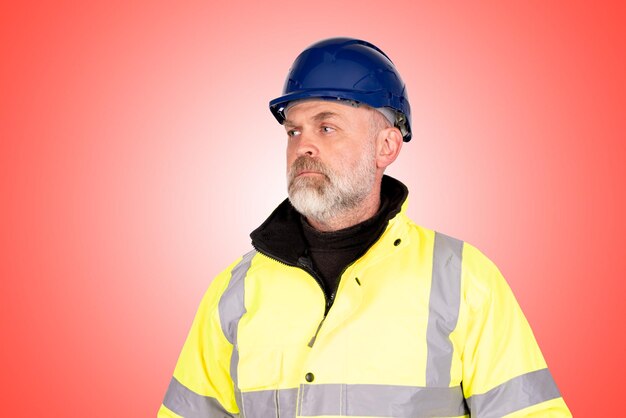 A construction worker in a blue hat and yellow hiviz coat on a light red background