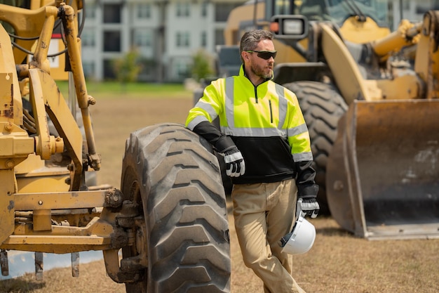 Construction worker on construction site Construction engineer worker in builder uniform on construction Machinery builder at buildings background Excavator loader tractor and buider worker