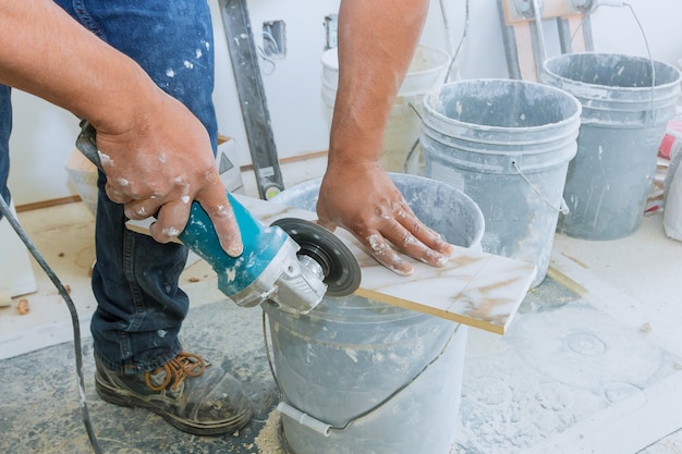 A construction worker cutting a tile using grinder