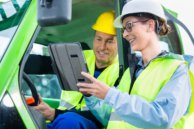 Construction worker discussing with engineer blueprints 