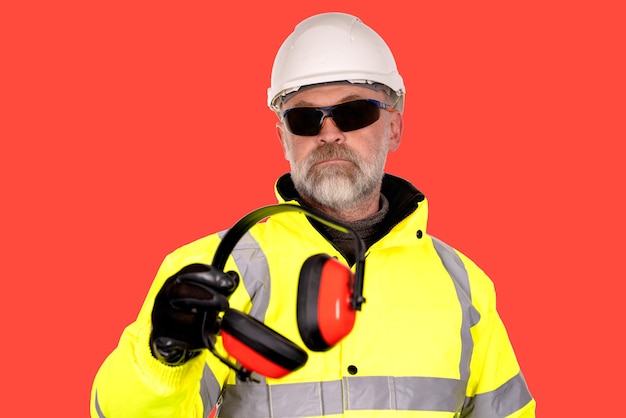 construction worker in hat coat and safety glasses  gives foamfilled padded ear defenders