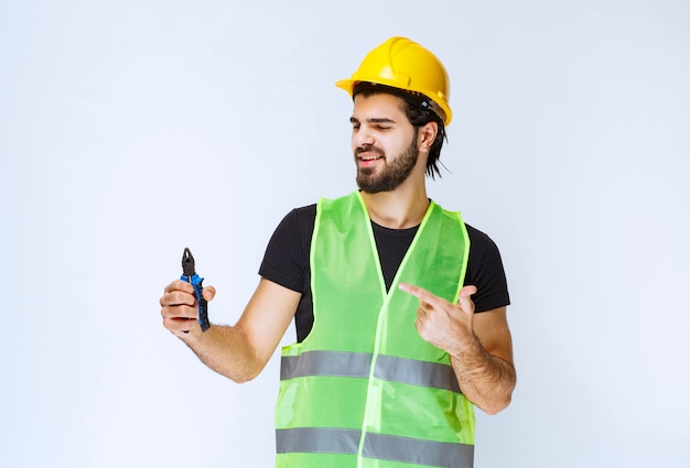 Construction worker holding blue pliers.