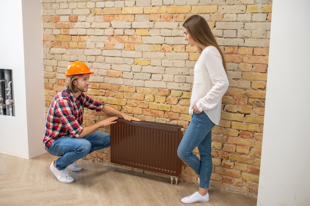 Construction worker in orange helmet talking to a customer