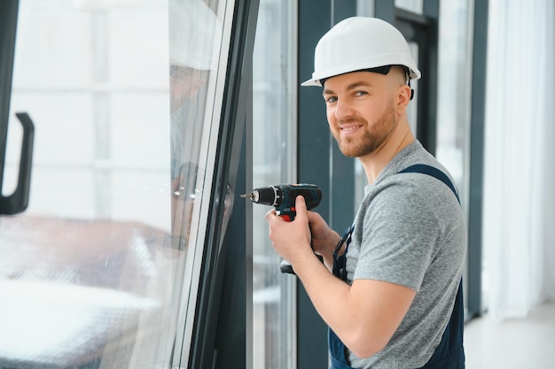 Construction worker repairing plastic window with screwdriver indoors, space for text. Banner design