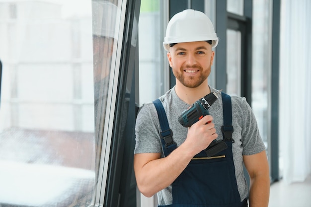 Construction worker repairing plastic window with screwdriver indoors, space for text. Banner design