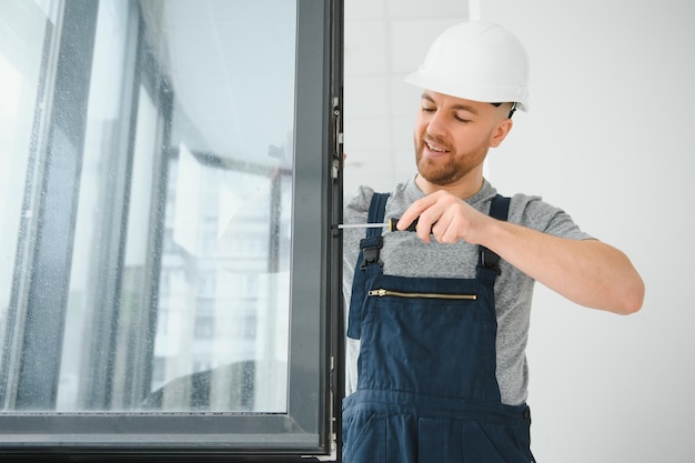 Photo construction worker repairing plastic window with screwdriver indoors space for text banner design