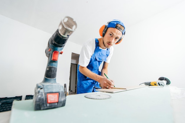 Construction worker in special uniform and ear protectors among tool draws in renovation