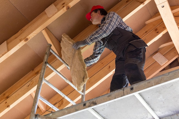 Construction worker thermally insulating eco wooden frame house