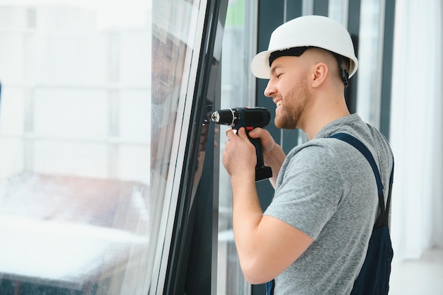 Construction worker using drill while installing window indoors