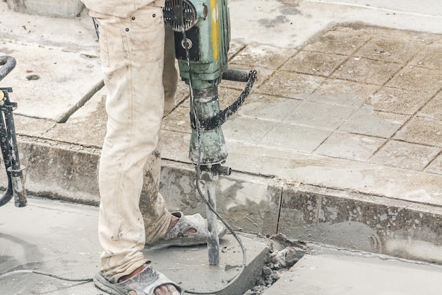 Construction worker using jackhammer drilling concrete surface