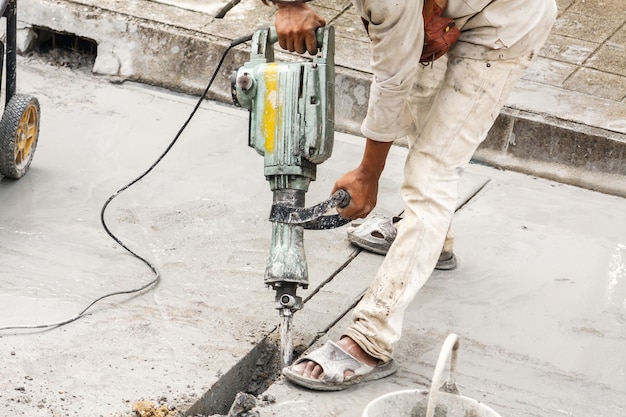 Photo construction worker using jackhammer drilling concrete surface