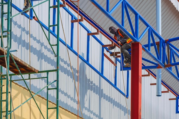 Construction workers are lifting metal framework for install on top of warehouse structure