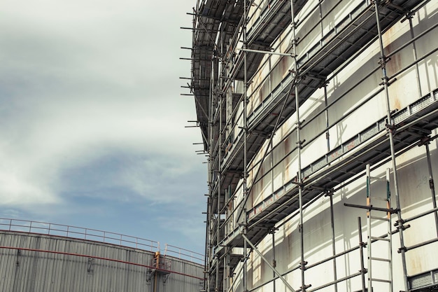 Construction workers tank oil installing scaffolding on site refinery