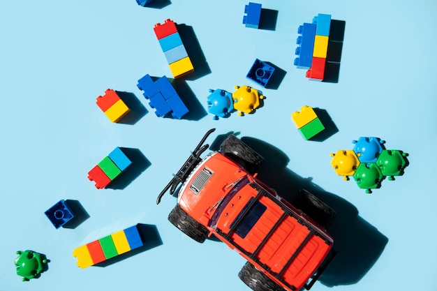 Constructor plastic and toy red jeep car on a blue background Top view flat lay