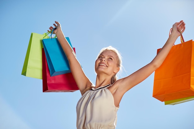 consumerism, sale and people concept - smiling woman with shopping bag rising hands