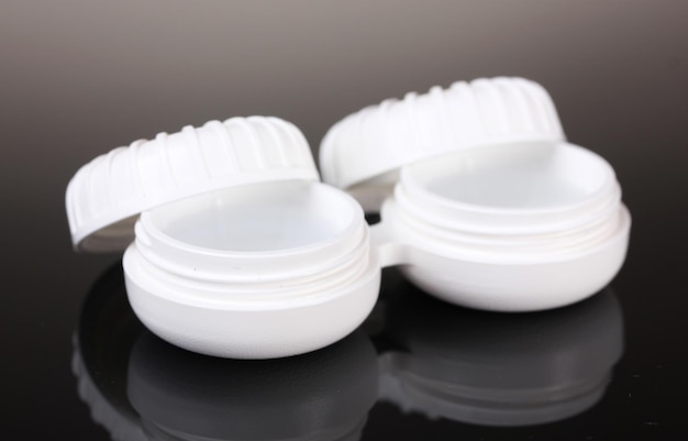 Contact lenses in containers on grey background