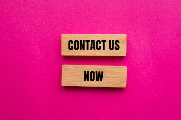 Photo contact us now message written on wooden blcoks with pink background conceptual contact us now symbol copy space