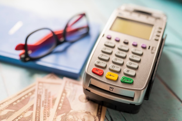 Contactless payment terminal with dollar bills with a notepad and glasses for payment