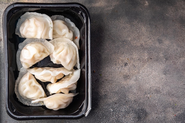 A container of dumplings with a black background