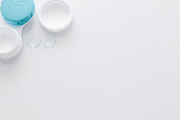 A container for lenses and two contact lenses lie on the side on a white background with space for t...