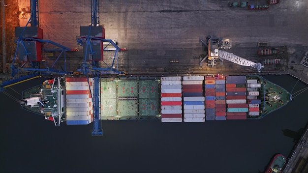 Container ship is unloading in the port in the evening aerial top down view