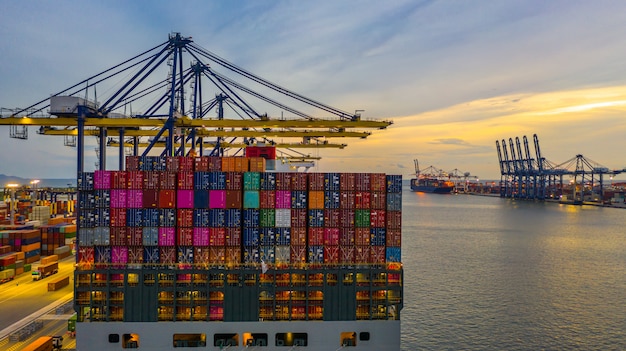 Container ship loading and unloading in deep sea port at sunset, Aerial view of business logistic import and export 