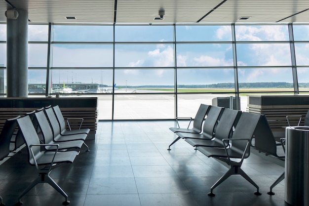 Contamporary airport terminal with empty chairs in a lounge area for waiting departure. Travel and transportation concept.