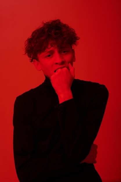 Photo contemplating young man in red lighted background