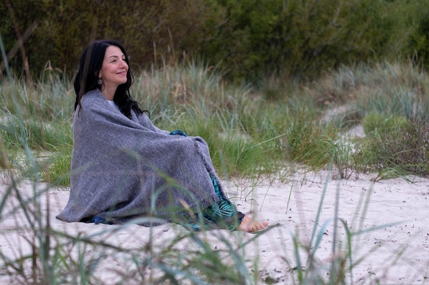 Photo a contemplative woman nestles in a soft shawl outdoors her smile reflecting an inner peace hinting at the grace of aging and the calm of emotional maturity