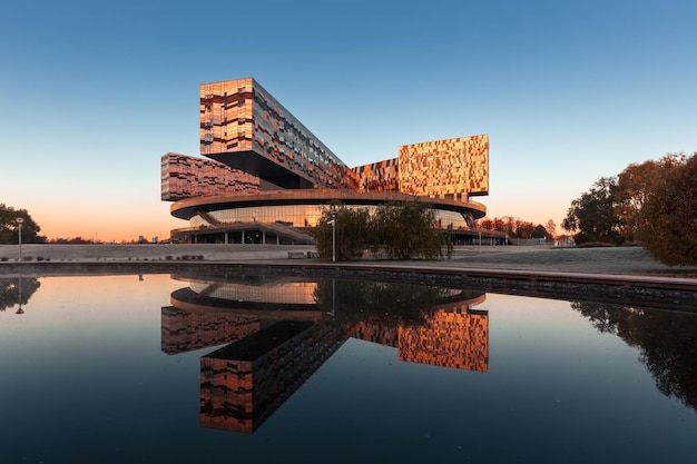 Contemporary building of Skolkovo Management School at sunrise reflected in a pond Moscow Russia