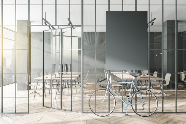 Contemporary glass partition and bike in stylish coworking office interior with empty black mock up poster and city view and daylight 3D Rendering