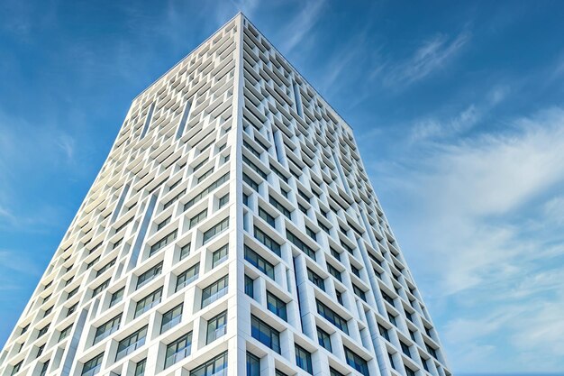 Contemporary high rise urban building with geometric design against cloudy blue sky in sunny day