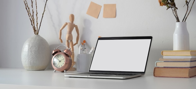 Contemporary workplace with open blank screen laptop computer, office supplies and decorations