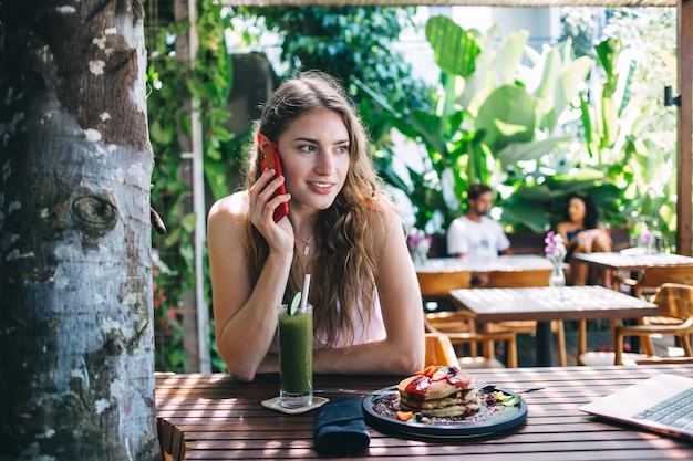 Contemporary young female freelancer using smartphone for call